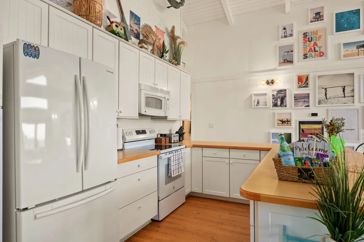A bright and welcoming kitchen featuring a white refrigerator, wooden countertops, colorful wall decor, and small potted plants. The space feels ready for family cooking, with ample surfaces for meal prep and a fresh, inviting atmosphere.