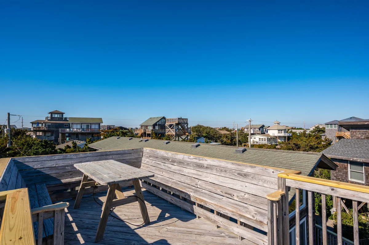 The image shows a wooden deck with a table and surrounding houses visible, emphasizing tranquil outdoor relaxation and opportunities for socializing. The scene suggests moments spent enjoying views, fresh air, and group conversations in a peaceful setting.